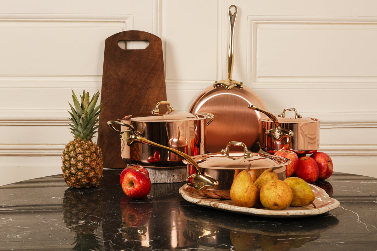 Mauviel M'Heritage M'150 B copper cookware set on a kitchen table